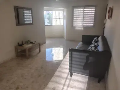 a living room with a black couch and two windows at La Guarida de Mela in Santo Domingo
