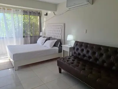 a bedroom with a bed and a couch and a window at beautiful Penthouse in the middle of Sosua walking distance to everything in Sosúa
