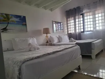 two beds in a white room with windows at beautiful Penthouse in the middle of Sosua walking distance to everything in Sosúa