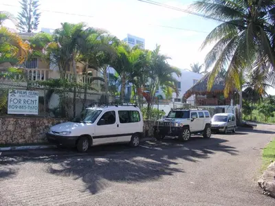 two cars parked on the side of a street at Waverider Apartments in Cabarete