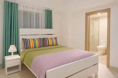 a white bedroom with a bed and a bathroom at Elegant Downtown Stay Santo Domingo in Santo Domingo