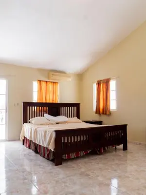 a bedroom with a large bed with orange curtains at 4BR Villa Newly Renovated-5 min to Playa Dorada H1 in San Felipe de Puerto Plata