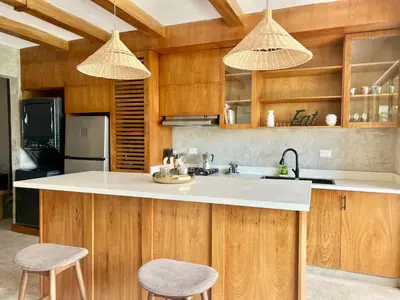 a kitchen with wooden cabinets and a sink and two stools at Villa Palmera in Las Terrenas