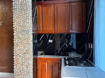 a kitchen with wooden cabinets and a stove top at Guest-House Caracol 2- 4 Pax, vista al mar in Las Galeras