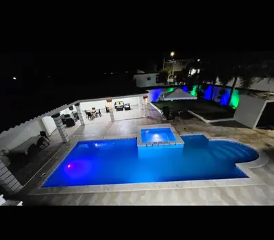 a large blue swimming pool at night at villa fortuna in Nagua