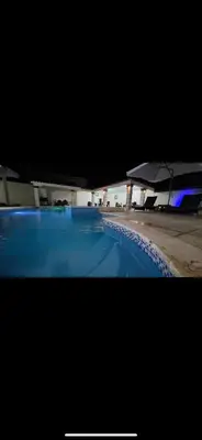 a large blue swimming pool with a building in the background at villa fortuna in Nagua