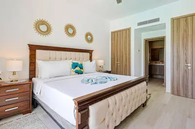 a bedroom with a large bed and two mirrors on the wall at Elegant 2BR Apt, Steps to Hard Rock in Punta Cana