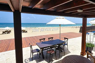 a table with chairs and an umbrella on the beach at Elegant 2BR Apt, Steps to Hard Rock in Punta Cana