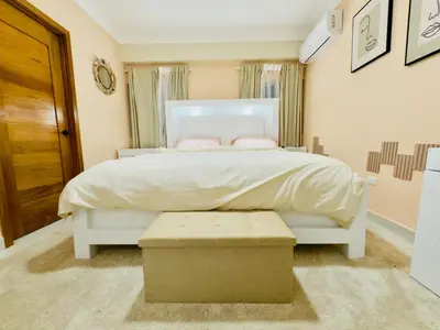 a bedroom with a large white bed with a ottoman at Luxurious 4 bedroom apartment near the beach in Ensanche Savica de Mendoza