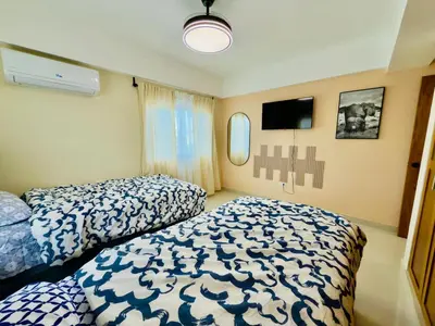 a bedroom with two beds and a tv on the wall at Luxurious 4 bedroom apartment near the beach in Ensanche Savica de Mendoza