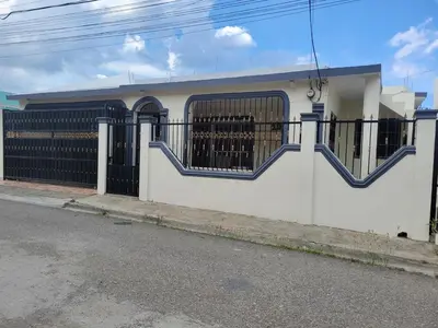 a white building with a gate and a fence at Spacious house with private parking in San Felipe de Puerto Plata
