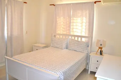 a bedroom with a white bed and a window at Comfortable Apartment, Torre Alta in San Felipe de Puerto Plata