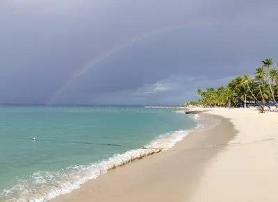 a rainbow over a beach with palm trees and the ocean at APARTAMENTO EXCLUSIVO Villa Privada Flamboyan in Bayahibe