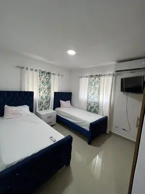 a bedroom with two beds and a flat screen tv at Beautiful residential area near Avenida España in Los Mameyes