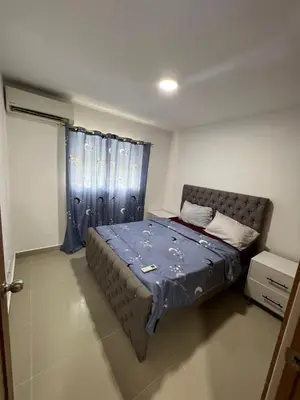 a bedroom with a bed with a blue comforter at Beautiful residential area near Avenida España in Los Mameyes