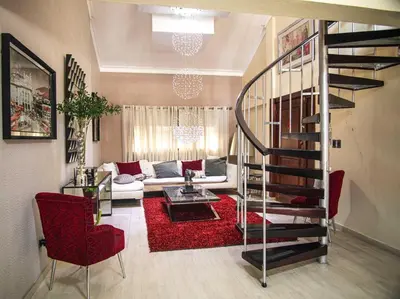 a living room with a spiral staircase and red chairs at Penthouse in Santo Domingo