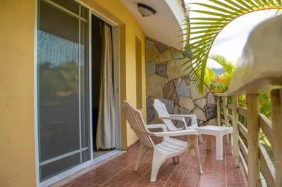 a porch with white chairs and a stone wall at Jarabacoa River Club & Resort in Jarabacoa