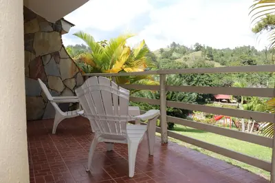 a porch with two white chairs and a stone wall at Jarabacoa River Club & Resort in Jarabacoa