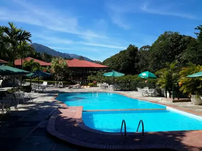 a large blue swimming pool with tables and umbrellas at Jarabacoa River Club & Resort in Jarabacoa