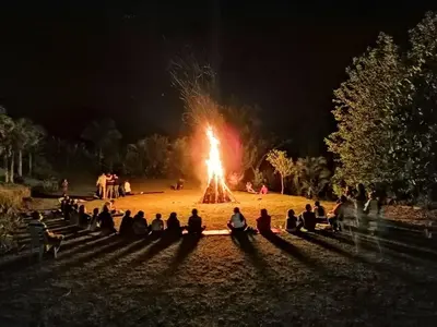 a group of people sitting around a fire pit at night at Jarabacoa River Club & Resort in Jarabacoa