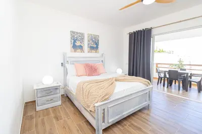 a white bedroom with a bed and a dining room at Luxury 1BR Oasis Paraiso Residence Bayahibe