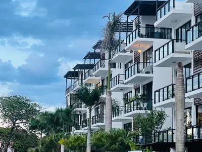 a building with palm trees in front of it at Beautiful Penthouse in Sunset Puerto Plata Gym, Pool in Puerto Plata