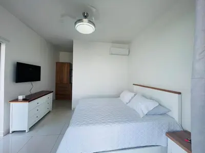 a bedroom with a white bed and a flat screen tv at Beautiful Penthouse in Sunset Puerto Plata Gym, Pool in Puerto Plata
