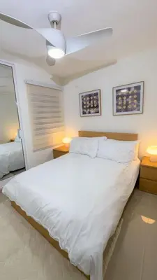a bedroom with a white bed with a ceiling fan at San Isidro Urban suite in Juan López