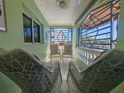 a room with chairs and a balcony with windows at 3 Bed, 2 Bath, Hot Water, Apartment near the beach, in Bani in Baní