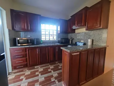 an empty kitchen with wooden cabinets and a window at Cozy apartment, AC, Wifi, 2BR, 2Bath, Bani, 1-B in Baní