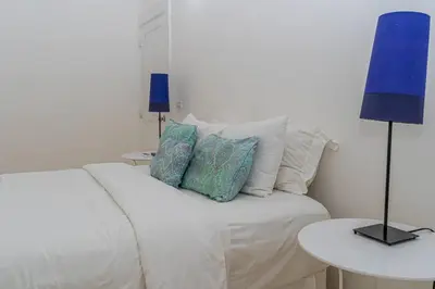 a bedroom with a white bed with pillows and a blue lamp at Las Marinas Los Nmada, 80 meters from Coson beach in Las Terrenas
