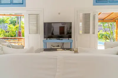 a living room with a tv and white furniture at Las Marinas Los Nmada, 80 meters from Coson beach in Las Terrenas