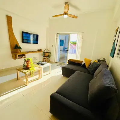 a living room with a black couch and a ceiling fan at Modern Central Ocean View and Jacuzzi Apartment in Santo Domingo