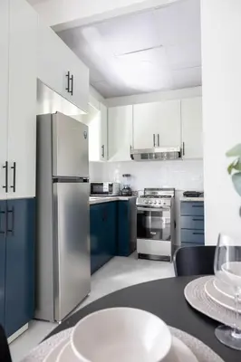 a kitchen with blue cabinets and a stainless steel refrigerator at Prado Garden Hotel in Monte Plata