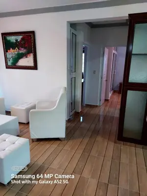 a living room with white furniture and a wooden floor at Stylish Apartment Steps from Puerto Plata Malecon in San Felipe de Puerto Plata