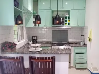 a kitchen with green cabinets and a table and chairs at Casa Brisa del Río in Las Terrenas