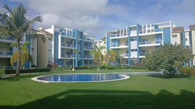 a large apartment complex with a swimming pool and palm trees at Eden Caribe Punta Vana in Punta Cana