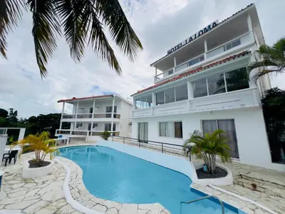 a hotel with a swimming pool in front of a building at Hotel La Loma in Miches