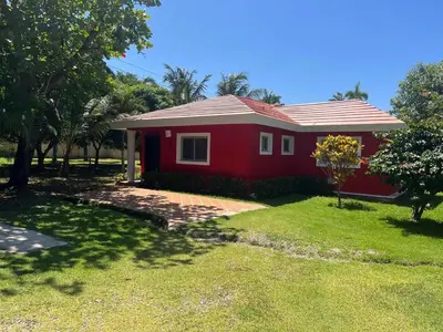 a red house with a green lawn in front of it at Villa near the beach in Cabarete