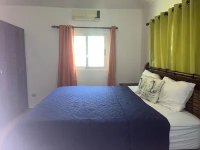 a bedroom with a bed with a blue comforter and a window at Villa amalu in Cabarete