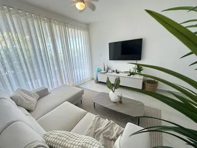 a living room with a white couch and a tv at A104 - PRADOS · Peaceful 2BR Poolside Retreat • Punta Cana Getaway in Punta Cana