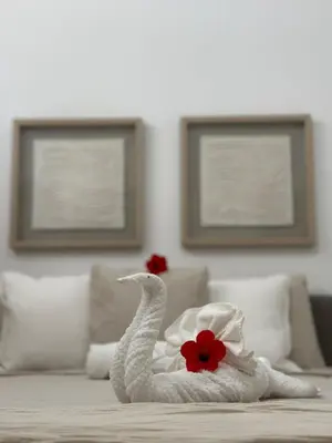 a white towel swan with a red flower on a bed at A104 - PRADOS · Peaceful 2BR Poolside Retreat • Punta Cana Getaway in Punta Cana