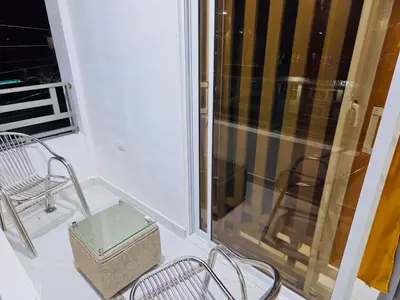 a balcony with two chairs and a glass window at Comfortable and warm apartment in Higuey