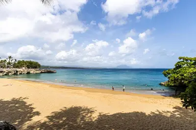 a beach with people swimming in the ocean at Galeria Beach Front, Top floor in Sosúa