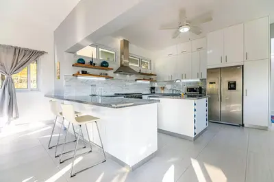 a large white kitchen with a counter and a stove at Villa real con piscina panorámica para más de 14 huéspedes in Sosúa