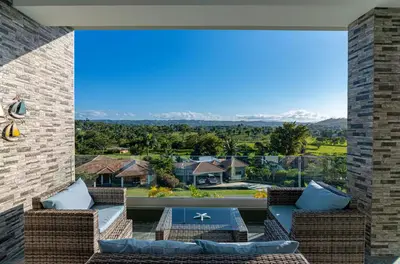 a patio with wicker furniture and a view of the mountains at Villa real con piscina panorámica para más de 14 huéspedes in Sosúa