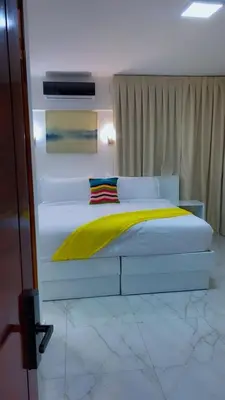 a bedroom with a white bed with a yellow blanket at Zile Hotel in Boca Chica