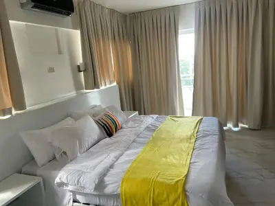 a bedroom with a white bed with a yellow blanket on it at Zile Hotel in Boca Chica