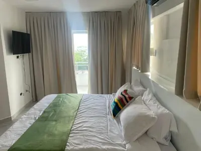 a bedroom with a large white bed with a window at Zile Hotel in Boca Chica