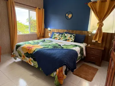 a bedroom with a bed with blue walls and a window at Brisa de mar in San Felipe de Puerto Plata